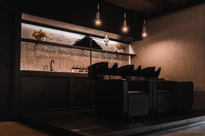 Zona lavaggio con poltrone scure e piastrelle decorative